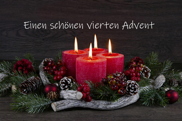 Roter Adventskranz mit vier brennenden Kerze zum vierten Advent.