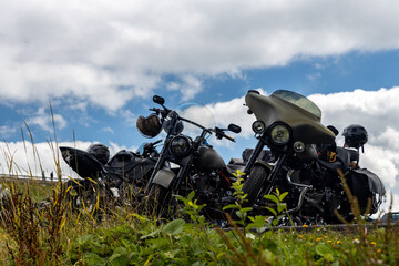 Old motorcycles in a mountain parking lot against the blue alpine sky