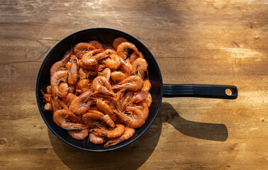 Cooking shrimp in a frying pan on a rustic old table