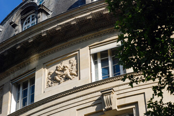 Obraz premium Facade of a house, building in Paris, the capital of France, with a sculpture of children angels on the wall. Photography of architecture in Europe.