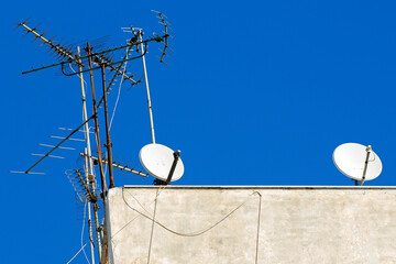 TV antennas and satellite dishes on the roof of a building in Athens, Greece. sunny day with blue...