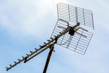 TV antenna on a pole against blue cloudy sky