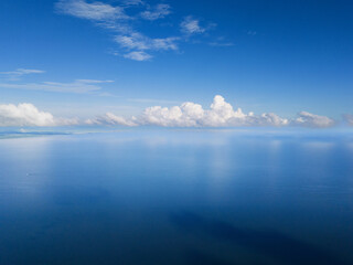 Serenity of open sea under clear blue sky with fluffy clouds