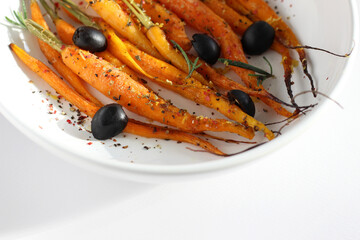 Fresh Carrots Roasted in Oven with Olive Oil, Salt and Pepper, Garnished with Rosemary and Olives. Healthy Colorful Food.