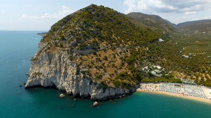 Aerial view of Saraceno Mount. It is a cliff on mediterranean Sea with a trekking path for mountain hiking. On the right is the beach of Mattinata, in province of Foggia, Puglia, Italy.