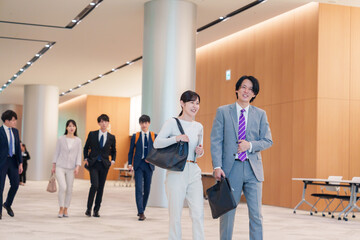 Fototapeta premium オフィスのホールで話しながら歩くビジネスパーソン