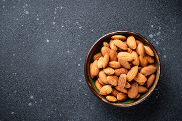 Almond nuts in bowl at black background. Top view.