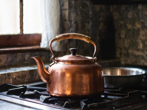 Tarnished copper kettle steaming on a stovetop in a cozy kitchen interior, exuding warmth and charm with rustic details and natural lighting. Generative AI - Powered by Adobe