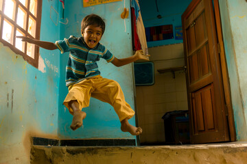 A young Indian boy bounds with energy, his laughter filling the room as he leaps over obstacles, his sense of adventure contagious.
