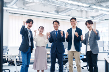 オフィスで笑顔でガッツポーズをするビジネスパーソン