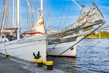 Two bows of a sailboat standing side by side near the pier.