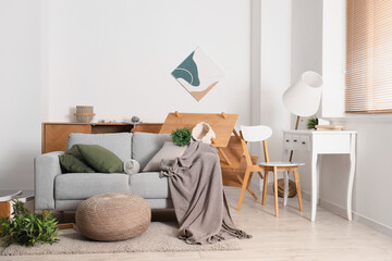 Interior of messy room with grey sofa and overturned furniture after earthquake