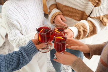 Friends with glasses of delicious mulled wine sitting at home, closeup