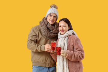 Happy couple with glasses of delicious mulled wine on yellow background