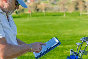 closeup elderly golfer marking points on tablet during golf tournament