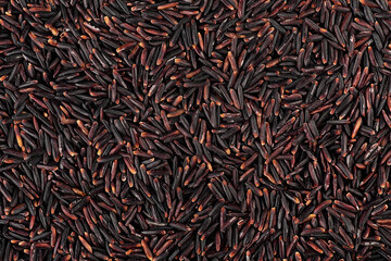 Raw black rice as background, top view. Dry organic black rice grains. Black glutinous rice, healthy eating and vegetarian diet.