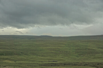 An abandoned farm house at a croft on a lush green hillside on the west coast of the Highlands of Scotland, under a cloudy sky. © Linda Harms
