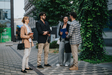 Fototapeta premium A group of business people engaged in a lively discussion outdoors in a city setting. They appear to be brainstorming ideas and strategies in an urban environment.