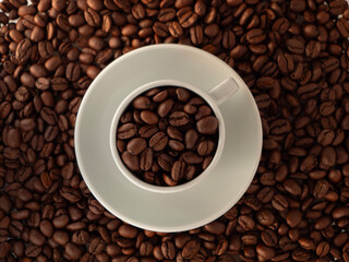 coffee cup filled with roasted coffee beans, the cup is on a background of coffee beans top view