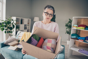 Photo of doubtful unsure lady wear pink sweatshirt choosing donation clothes indoors room home house