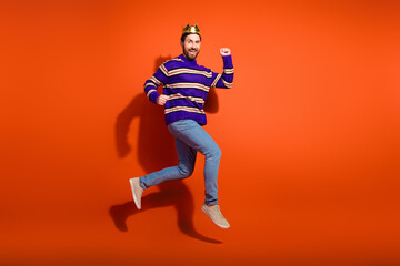 Naklejka premium Full body photo of attractive young man winning king running dressed stylish striped purple clothes isolated on orange color background