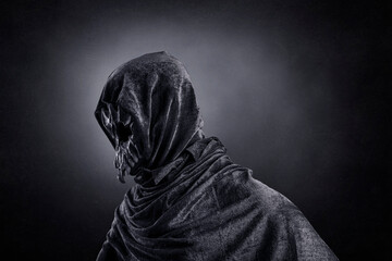 Creepy figure with animal skull at night over dark misty background