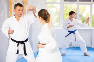 Fototapeta premium Woman and man in kimono sparring together in gym during karate training