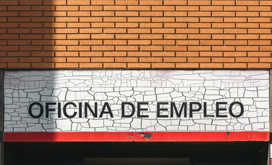 Employment office sign in Spanish on a brick wall indicating job services available for local...