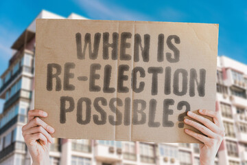 The phrase 'When is re-election possible?' on a banner in a person's hand. Human holds a cardboard...