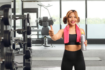 Fototapeta premium ilipina woman in sportswear holding a water bottle in a gym
