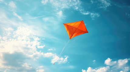 Orange kite flying in blue sky with scattered clouds Outdoor recreational activity, symbolizing freedom and joy