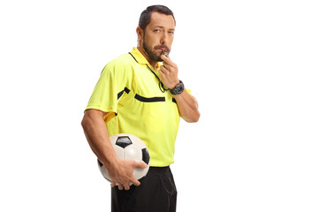 Football referee blowing a whistle and holding a ball