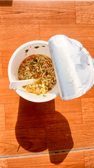 Blitar Indonesia, November 21, 2024: Cup instant noodles from Pop Mie products on a brown table background.