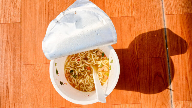 Cup instant noodles from Pop Mie products on a brown table background.