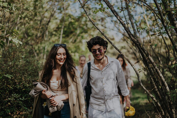 A group of friends are enjoying a relaxing stroll through a sunlit forest, surrounded by lush...
