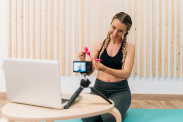Smiling fitness blogger recording exercise video with vaginal weights