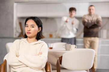 Obraz premium Upset young woman not talking after disagreement with father and husband standing behind