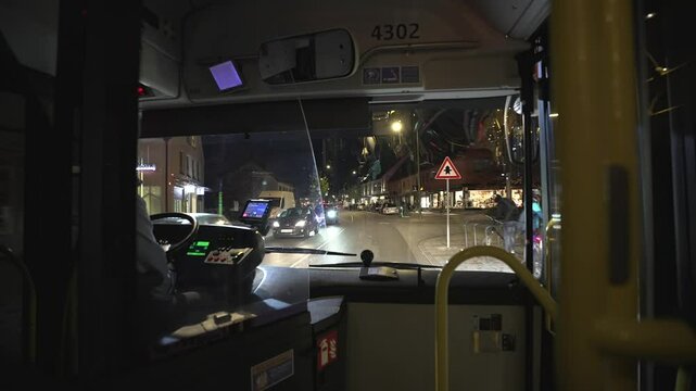 View from the windshield of a bus on the road in the night city of Munich, Germany. View through the drivers window on a city bus traveling the route at night in Europe. Public transportation. 