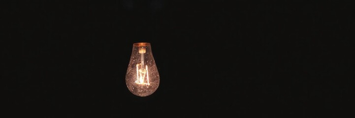 A glowing light bulb standing out in the dark evening, symbolizing the importance of keeping the light on, energy efficiency, night, illuminated