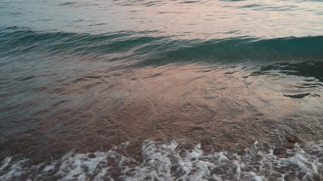Waves gently lap at shore during stunning sunset over ocean. Golden sunlight reflects off waves as they roll onto shore, creating tranquil atmosphere at sunset by sea. Montenegro summer, Canj