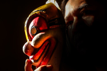 Man with clown mask in dark place