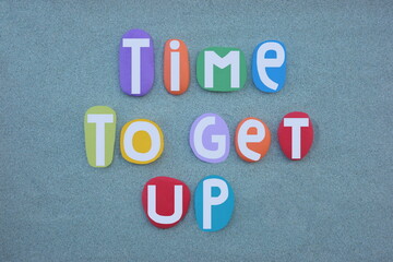 Time to get out, creative slogan composed with hand painted multi colored stone letters over green...