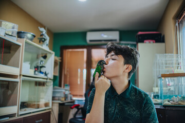 A young person affectionately interacting with a colorful parrot, showcasing a bond between human...