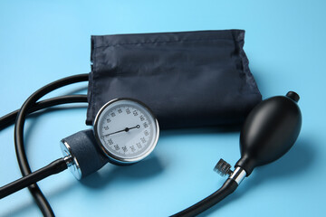 Blood pressure measuring device on light blue background, closeup