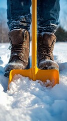 Man standing in deep snow with boots and shovel during winter activities