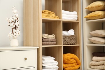 Home textile organization. Folded towels, blankets and pillows on shelving units indoors