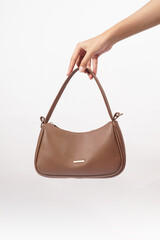 Women's luxury handbag in girl's hand, brown handbag purse, leather bag isolated on white background