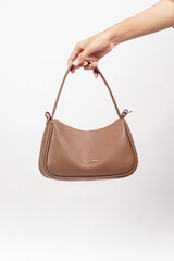 Women's luxury handbag in girl's hand, brown handbag purse, leather bag isolated on white background