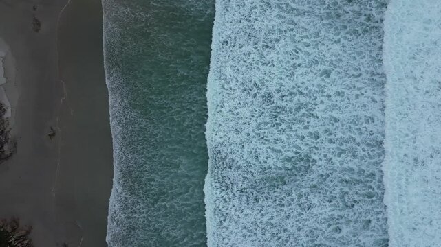 Top down aerial footage of the Atlantic Ocean waves on the sandy shore of Caion city, Spain