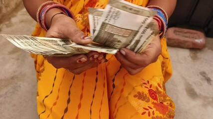 An Indian female counting 500 rupees Indian currency notes.